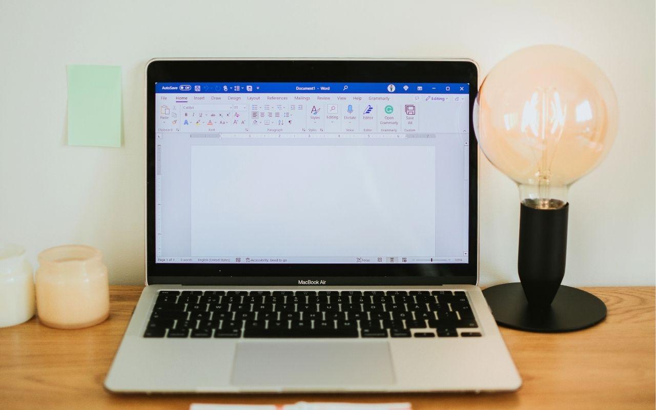 A laptop displaying a blank Microsoft Word document, used to format and create a professional resume.